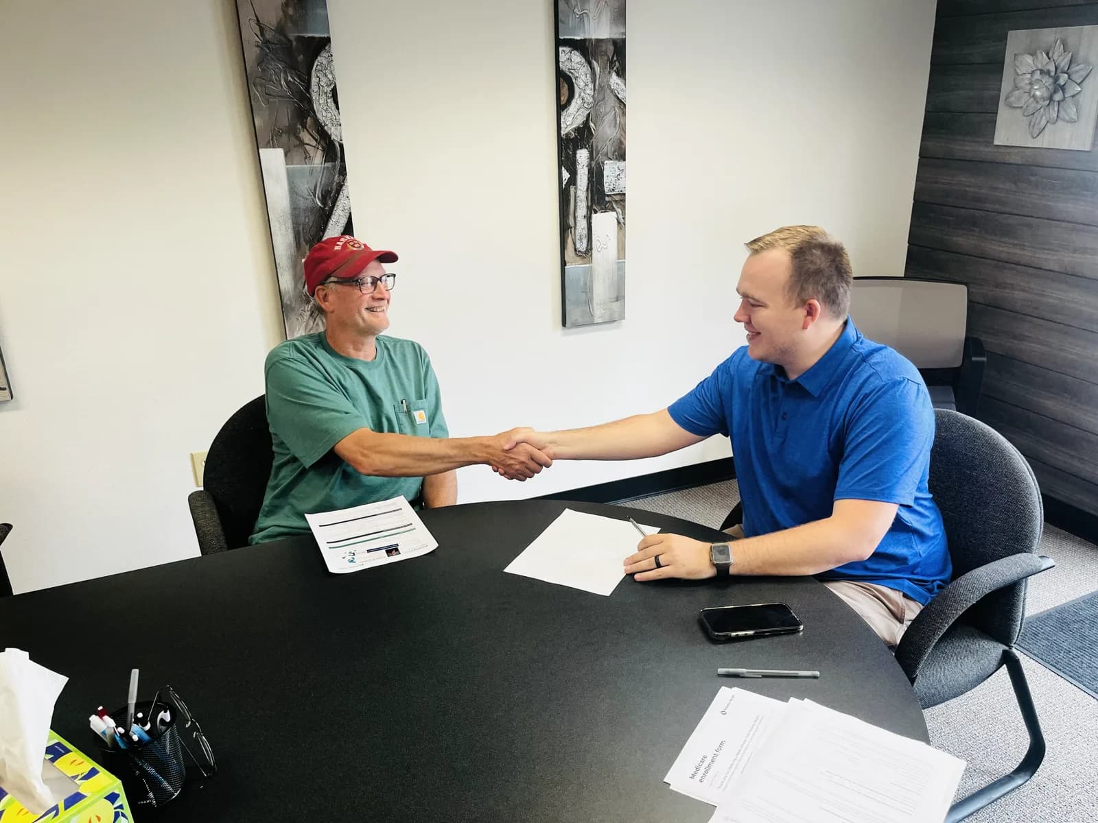 Hunter Klaassen shaking hands with a client after helping them enroll in Medicare at his Jackson, MI office